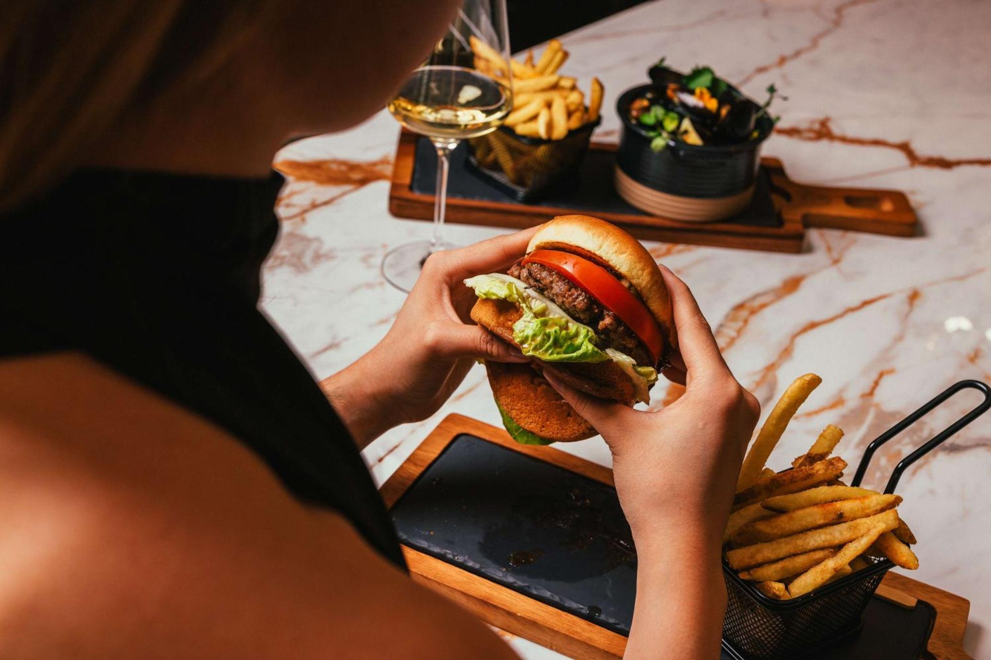 Hotel Hilton Vienna Plaza Esterno foto A burger with chips and a glass of wine